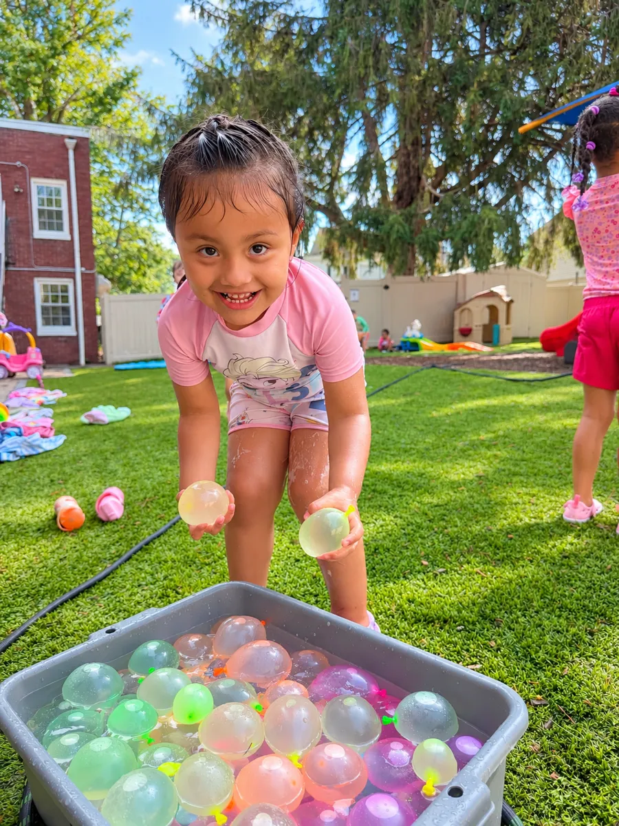 Child playing with water balloons in the backyard